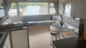 Ein gemütlicher Wohnbereich mit einer Couch, einem Esstisch und einer Küchenzeile mit Spüle und Schränken.