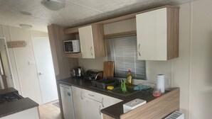 Eine kleine Küchenzeile mit Mikrowelle, Toaster, Wasserkocher und kleinem Kühlschrank.