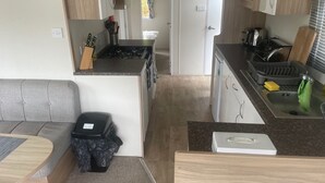 Eine kompakte Küche mit einem grauen Sofa, einer kleinen Mülltonne und einer Mikrowelle.