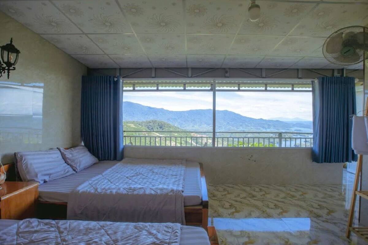 Une chambre avec deux lits, un ventilateur et une vue sur les montagnes.