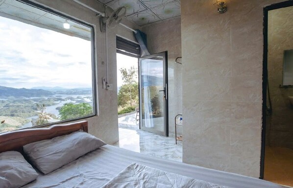 A bedroom with a large window offering a view of a valley and mountains. - Homestay A Suy Ta Dung (Ta Dung)