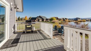 Une terrasse avec un barbecue, une vue sur les maisons de l’autre côté d’un lac et un ciel dégagé.
