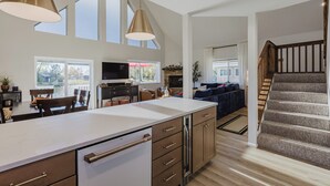 Une cuisine spacieuse dotée d’un grand îlot central, de meubles en bois et de luminaires suspendus.