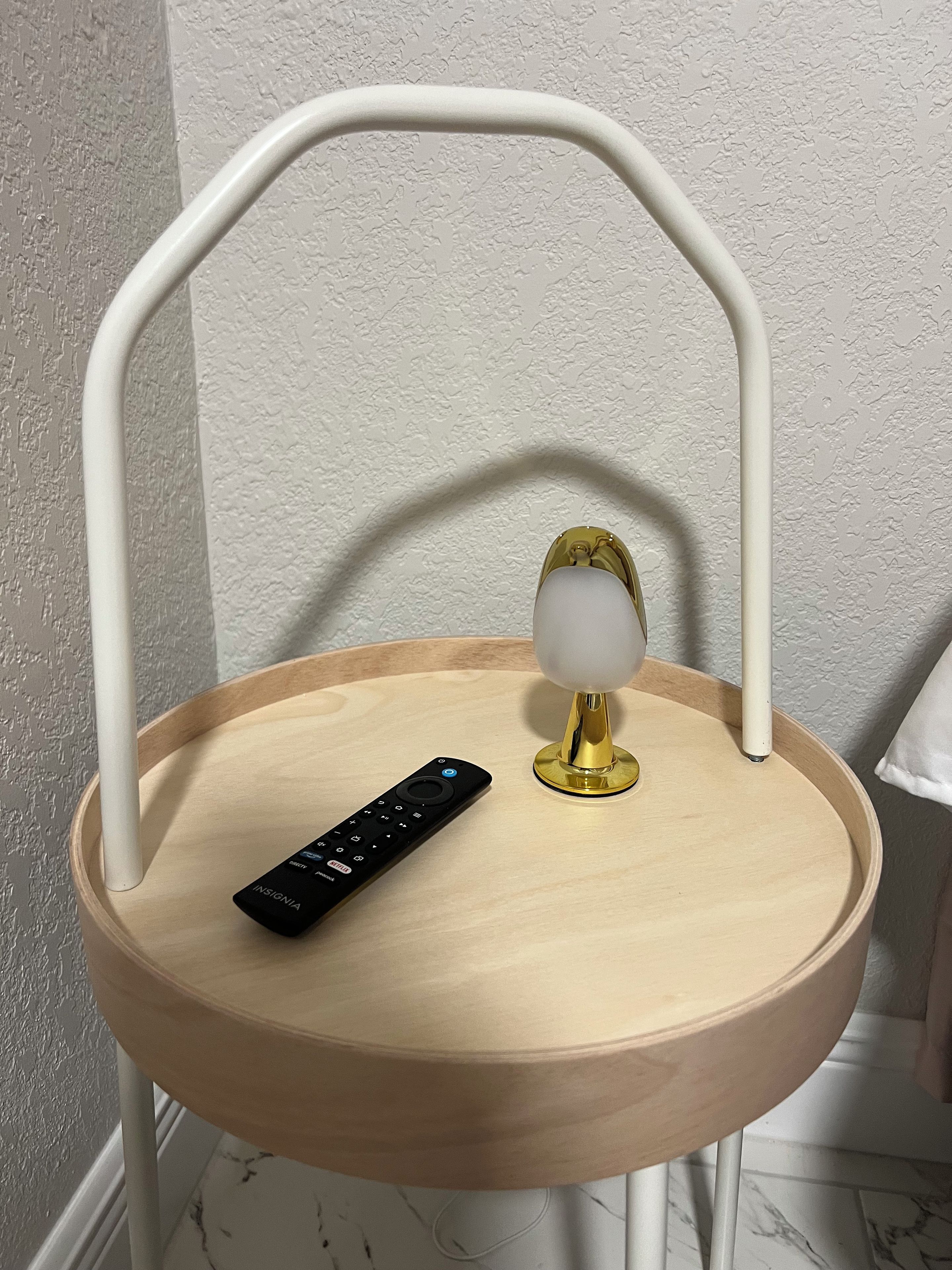 Une chaise en bois avec une structure en métal blanc et une télécommande posée dessus.