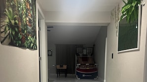 Un pasillo con un aro de baloncesto, un tapiz floral y una puerta que da a otra habitación.