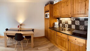 Une cuisine de taille réduite avec des meubles en bois, un plan de travail noir et un four à micro-ondes.