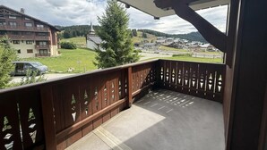 Un balcon donnant sur une ville, une clôture en bois et un ciel dégagé.