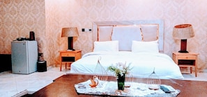 Een hotelkamer met een groot bed, twee nachtkastjes, een dressoir en een salontafel met decoratieve objecten.