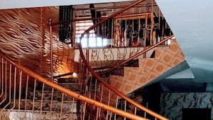 A marble staircase with ornate metal railings and a decorative table at the bottom.