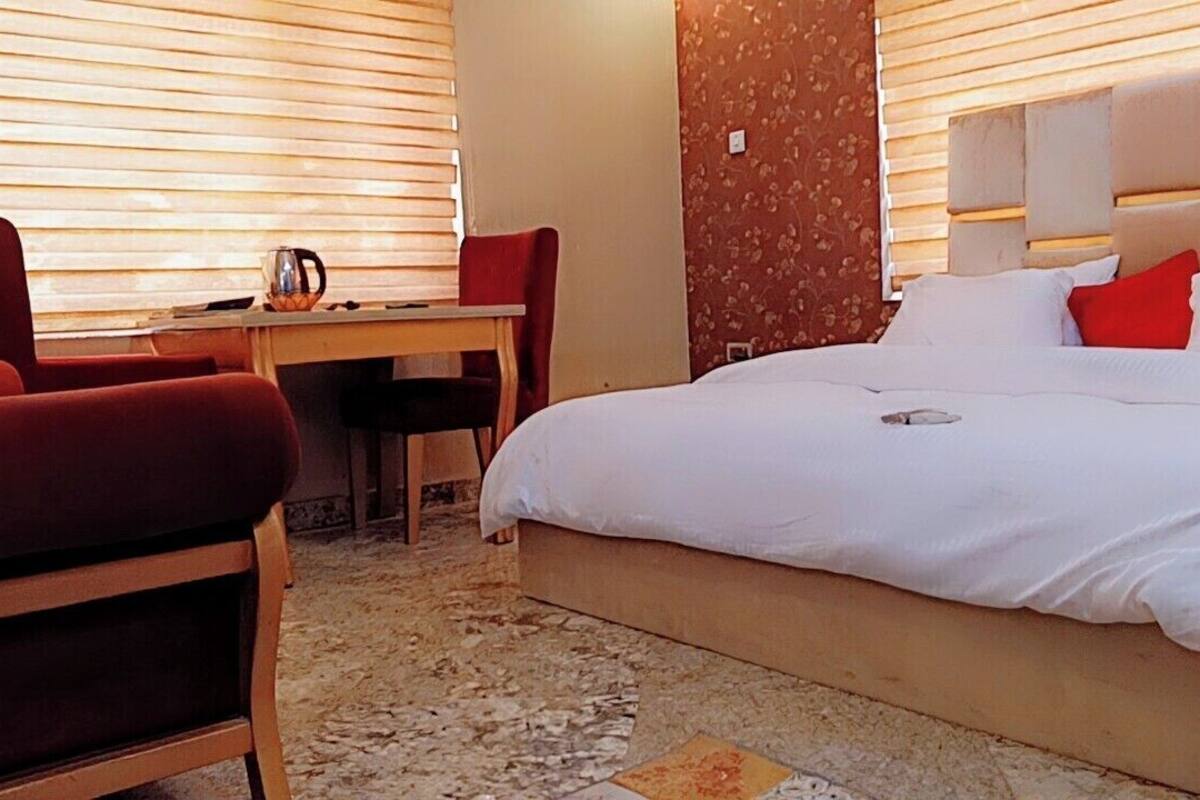 Une chambre d’hôtel avec un grand lit, un bureau et deux chaises rouges.