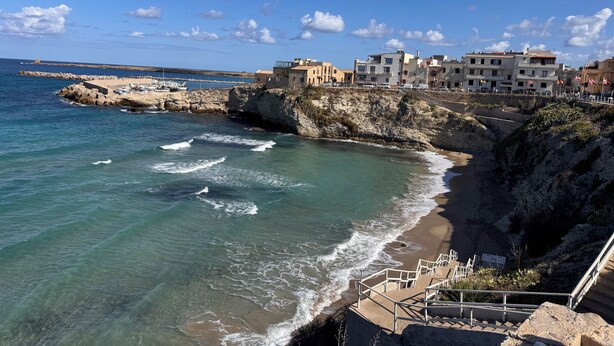 A coastal town with buildings along the cliffside, a sandy beach, and a rocky shoreline. - Vacation Home La Dolce Vita (Terrasini)
