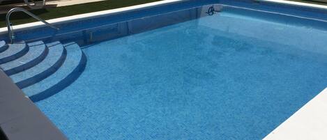 A rectangular swimming pool with a tiled edge and a built-in ladder.