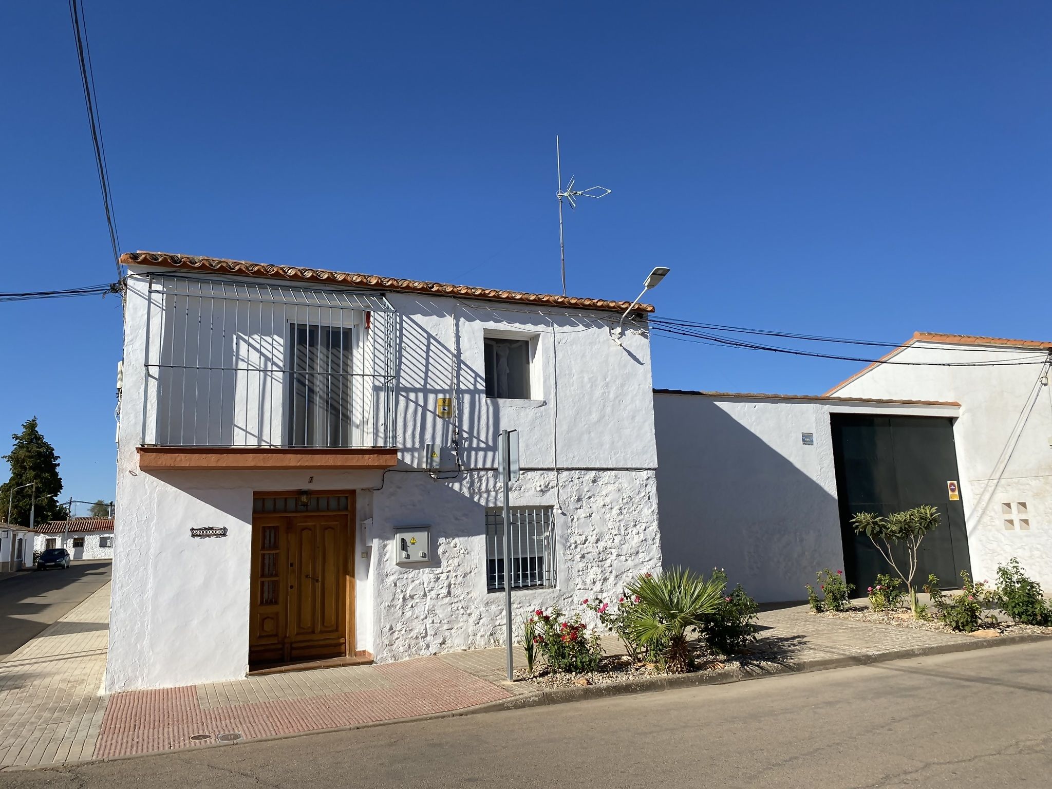 A two-story building with a white facade, a wooden door, and a small balcony.
