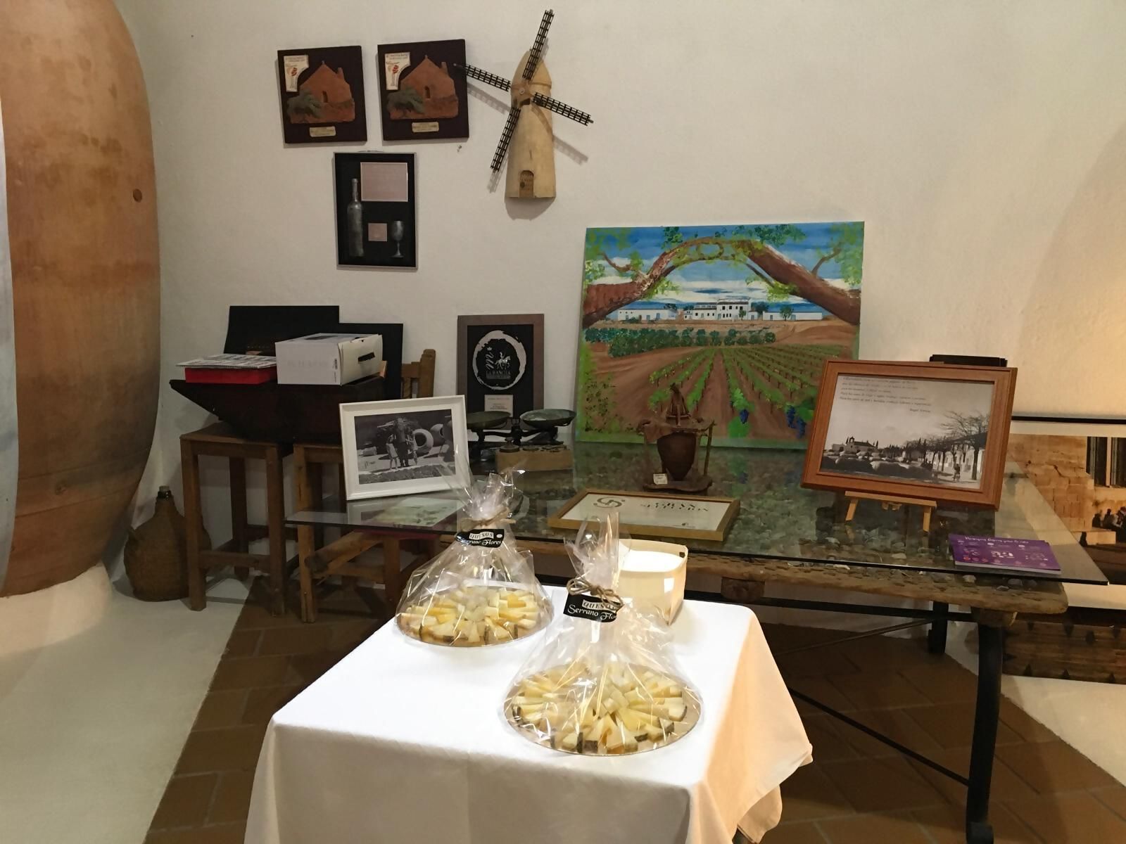 A room with a table displaying cheese, framed pictures, and a windmill model.