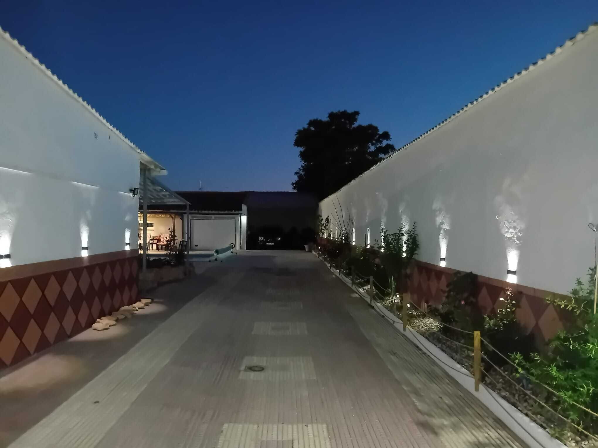 Un pasillo con una zona de estar al aire libre techada, un garaje y una fila de plantas a lo largo de las paredes.