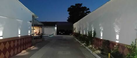 Un pasillo con una zona de estar al aire libre techada, un garaje y una fila de plantas a lo largo de las paredes.