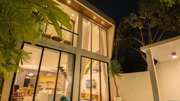 Una casa moderna con piscina, comedor y sala de estar con un ventanal grande.