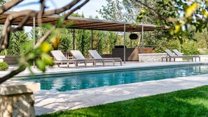 Une piscine avec des chaises longues et une pergola.