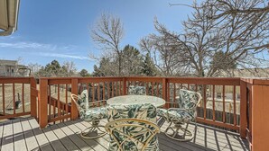A wooden deck with a round table and chairs, surrounded by a wooden railing. - Dover Court • 2BR Red Rocks Basecamp in Lakewood (Lakewood)