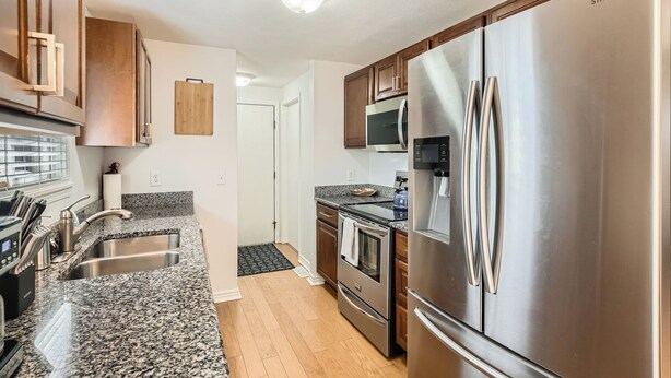 A modern kitchen with stainless steel appliances, granite countertops, and wooden cabinets. - Dover Court • 2BR Red Rocks Basecamp in Lakewood (Lakewood)