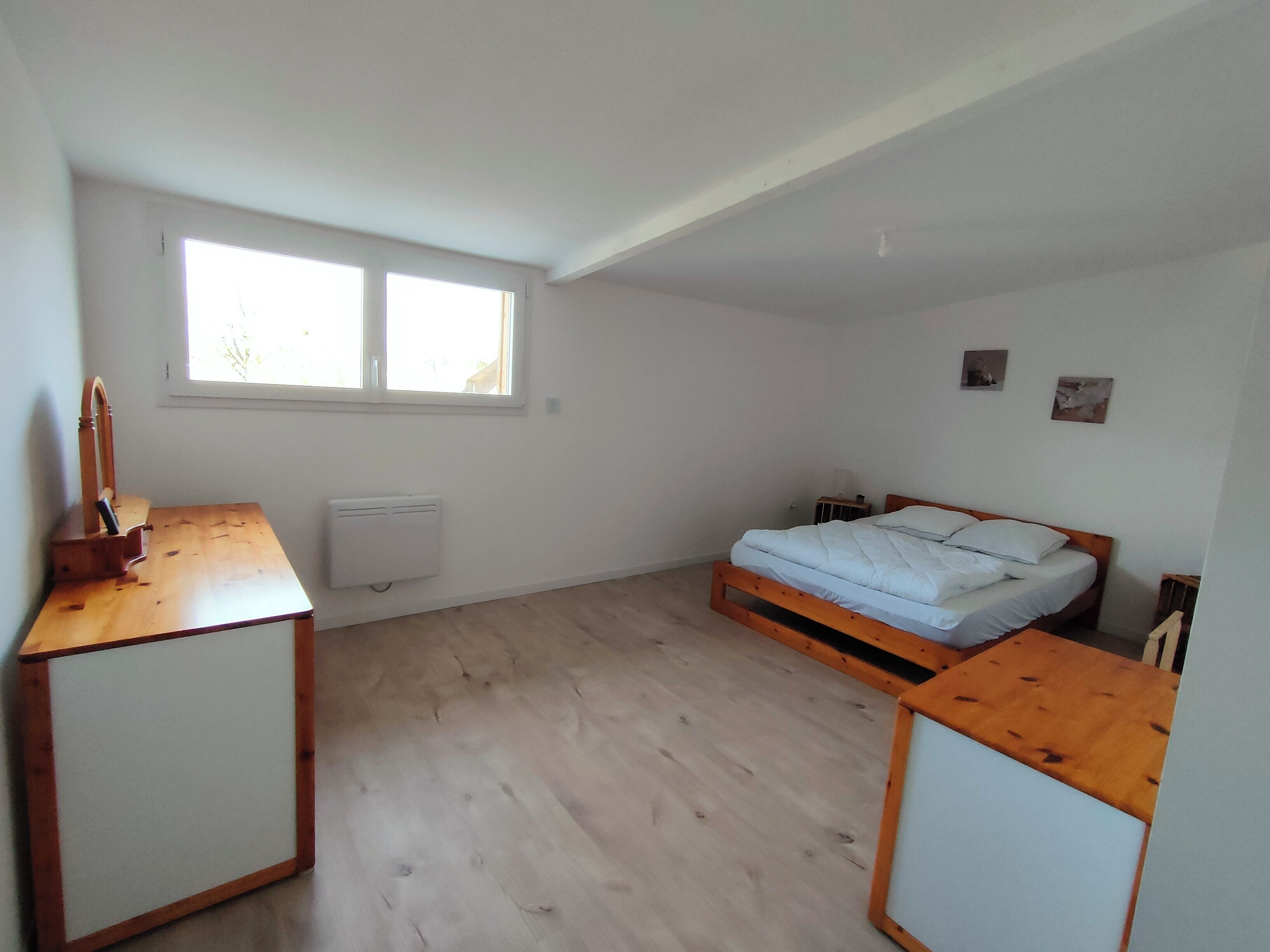 Een lichte, kleine kamer met een bed, bureau en radiator.