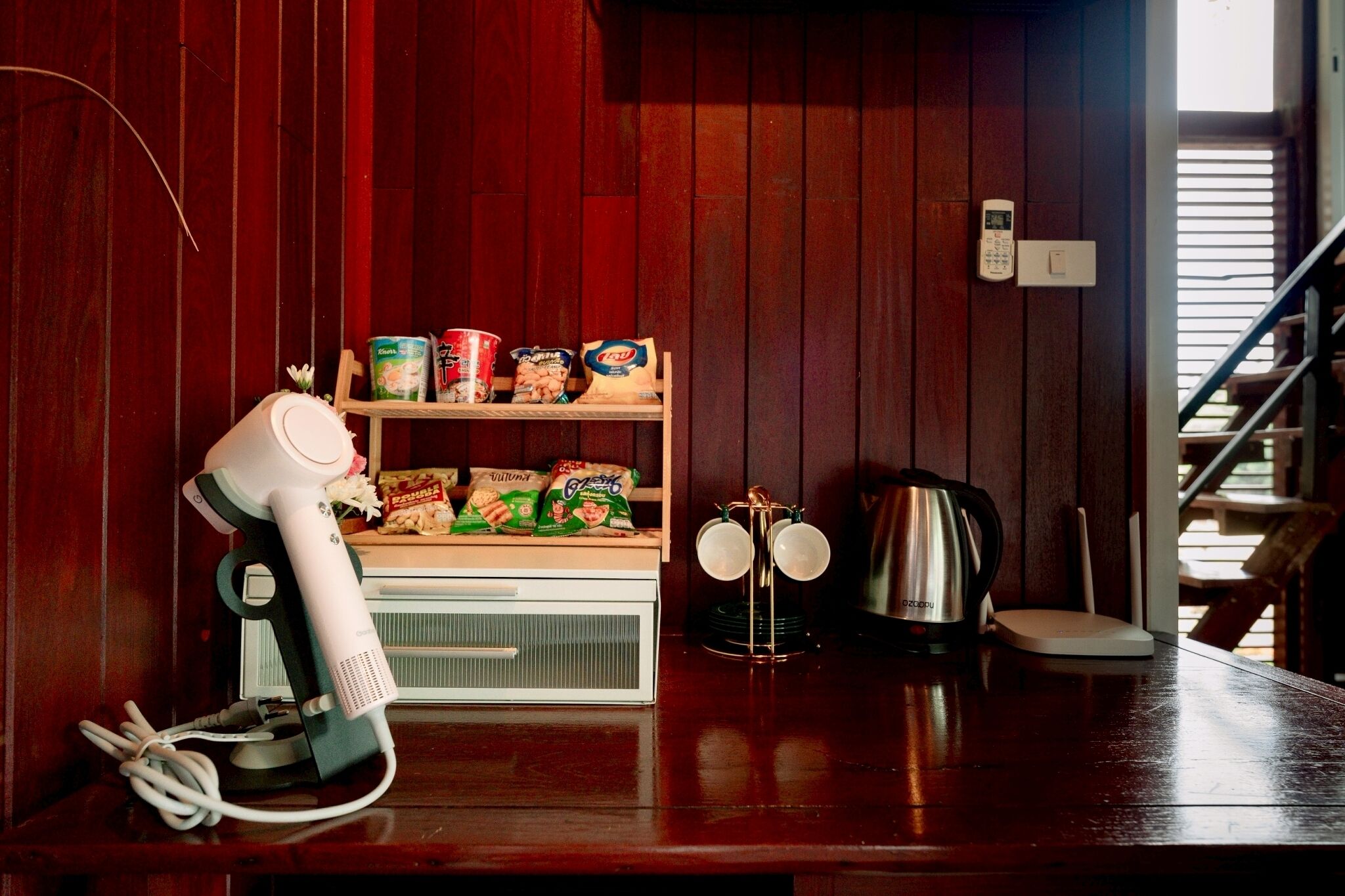 A kitchen with a white coffee maker, a kettle, and a shelf with food items.