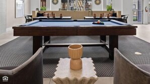 A spacious indoor pool area with a pool table, comfortable seating, and decorative lighting. - Bright 2BR Flat w/ Balcony + Pool | Walk to SoCo (Austin)