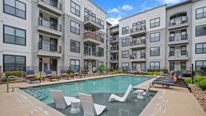 A modern apartment building with a swimming pool, outdoor seating, and balconies. - Modern 2BR Loft w/ Pool + Balcony in Heart of SoCo (Austin)