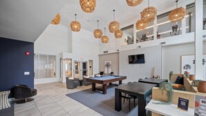 A spacious indoor area with a pool table, seating, and a reception desk.