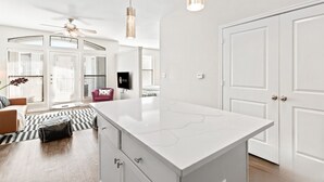A modern kitchen with a large island, white cabinetry, and pendant lighting.