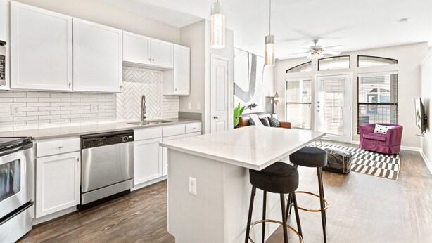 A modern kitchen with white cabinetry, stainless steel appliances, and pendant lighting.