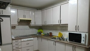 Cozinha com armários brancos, micro-ondas, fogão e pia.
