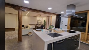 A modern kitchen with a central island, built-in appliances, and a dining area in the background.