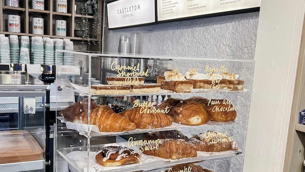 Une vitrine de boulangerie présentant diverses pâtisseries et le menu d’un café.
