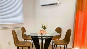 A dining area with a round glass table and four brown chairs. - The Retro duplex unit (Boise)