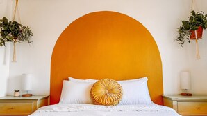 A bedroom with a large bed, white bedding, and a distinctive orange arch above the headboard. - The Retro duplex unit (Boise)