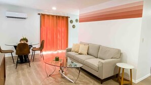 A modern living room with a sofa, a glass coffee table, and a dining area with chairs and a table. - The Retro duplex unit (Boise)