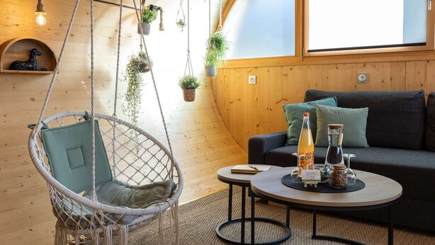 A cozy room with a hanging chair, a sofa, a small table with drinks, and plants. - Cocci-vert à L'oasis des Coccinelles (Sainte-Croix-aux-Mines)