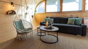 A cozy room with a hanging chair, a sofa, a coffee table, and large windows. - Cocci-vert à L'oasis des Coccinelles (Sainte-Croix-aux-Mines)