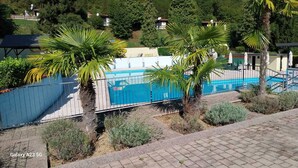 Ein Schwimmbecken, umgeben von Palmen und von einem Zaun.