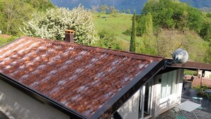 Ein modernes Haus mit einem geneigten Dach, einer Terrasse mit Gartenmöbeln und einem schönen Bergblick.