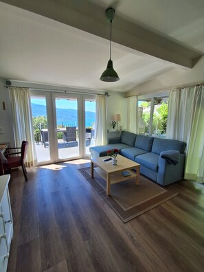 A spacious living room with a sofa, a coffee table, and a view of the outdoors. - Dream view of Lake Garda (Tignale)