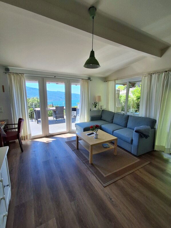 A spacious living room with a sofa, a coffee table, and a view of the outdoors. - Dream view of Lake Garda (Tignale)