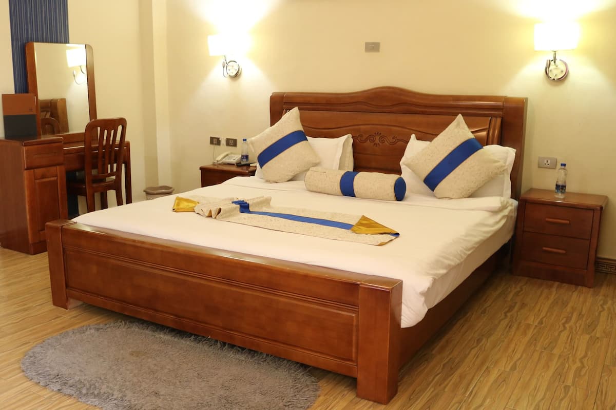 A neatly made bed with a wooden headboard, a bedside table with a lamp, and a small nightstand with a water bottle.
