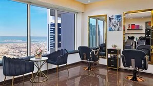A modern salon with large windows offering a city view, several salon chairs, and a well-organized reception area.