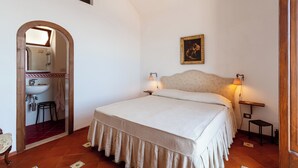 Una camera da letto con un letto, due lampade da comodino, un comodino, uno specchio e uno sgabello.