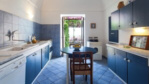 Una cucina con mobili blu, un lavello bianco e un tavolo da pranzo con sedie.