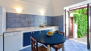 Una cucina con mobili azzurri, un'lavastoviglie bianca, un lavello e un tavolo rotondo con sedie.