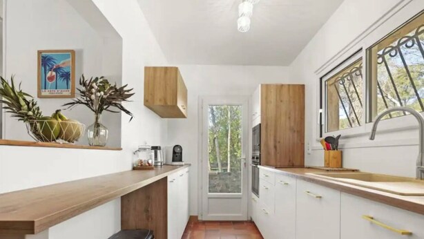 A compact kitchen with white cabinets, a wooden countertop, and a window with a view of greenery.