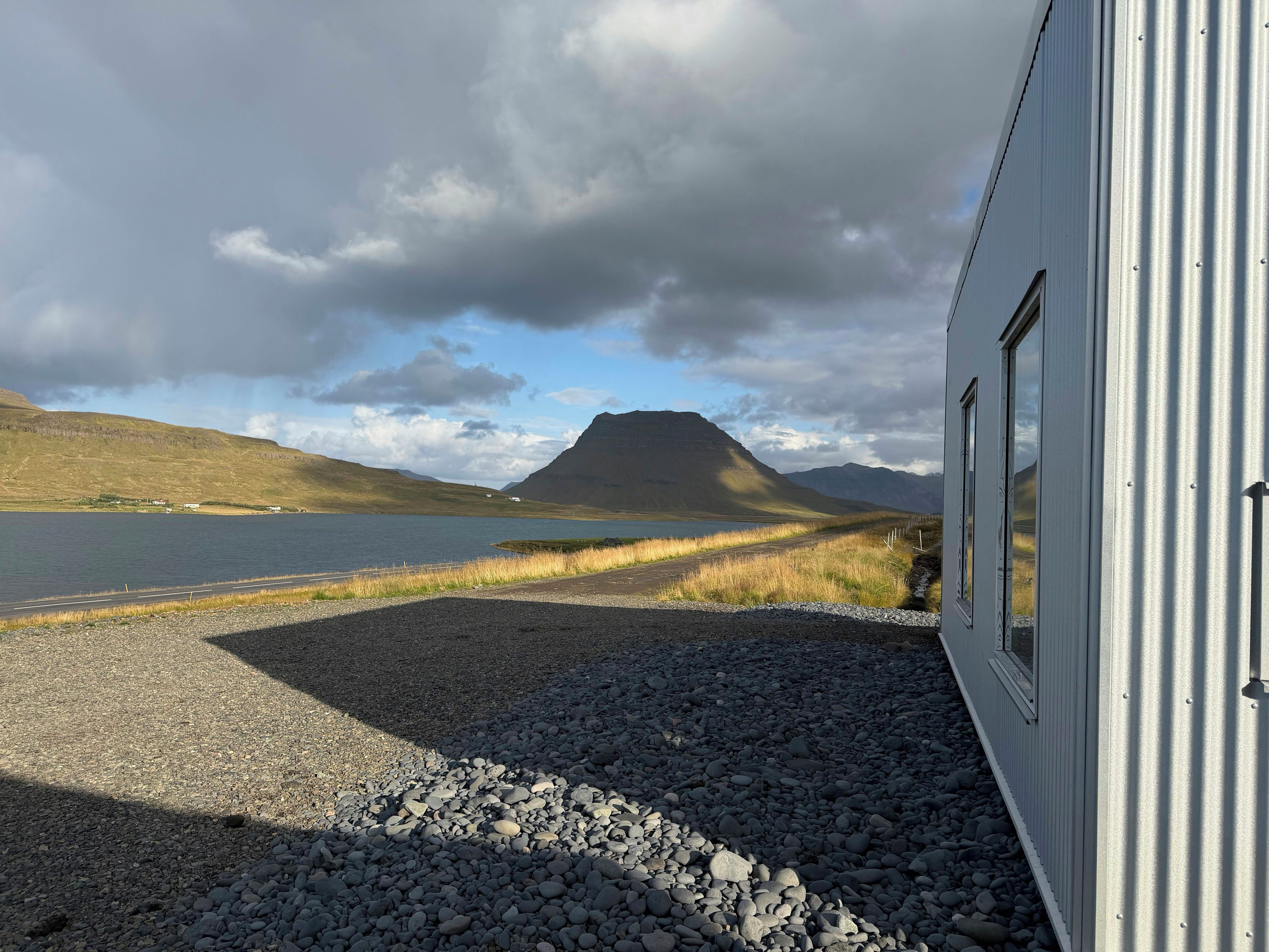 A gravel path leading to a body of water with a mountain in the distance.